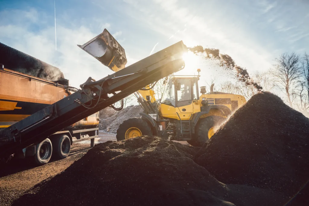 Heavy machinery moving earth and biomass in compost works or landfill